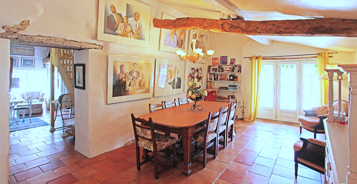 Large gite dining room with doors to rear terrace and opening to a seating area and the kitchen